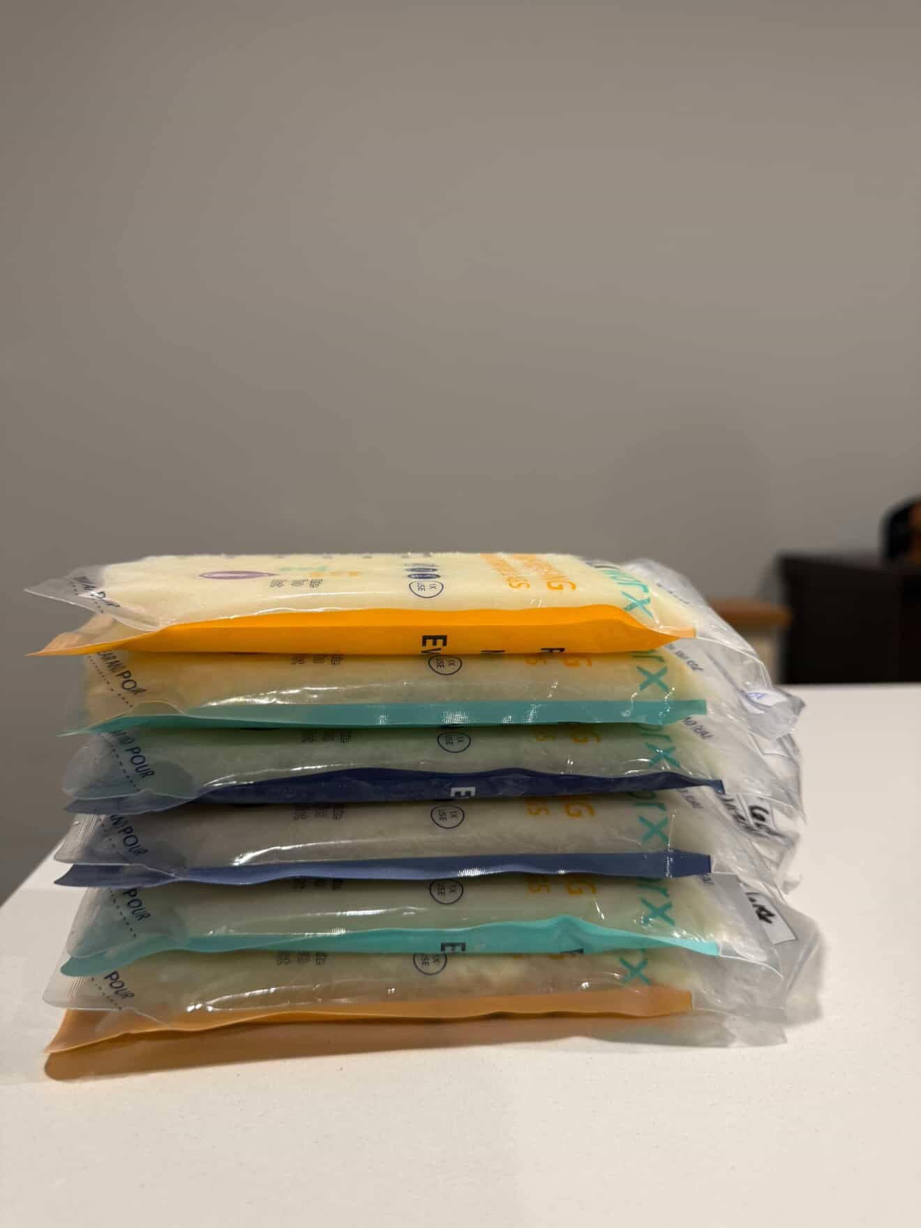 Stack of transparent packages with colorful labels on a white surface.